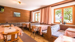 A cozy restaurant with wooden walls, large windows, and a mix of tables and booths. - Apartment in Maishofen near Ski Slopes (Maishofen)