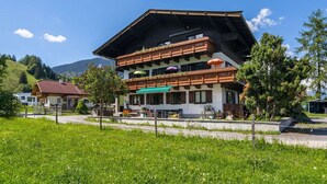 A two-story building with a sloped roof, balconies with wooden railings, and outdoor seating areas. - Apartment in Maishofen near Ski Slopes (Maishofen)
