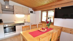 Eine Küche mit Holzausstattung, einer Mikrowelle, einem Backofen und einem Esstisch mit Stühlen.