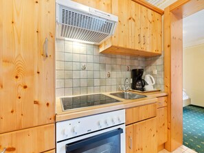 A kitchen with wooden cabinets, a gas stove, a built-in oven, a sink, and a coffee maker. - Apartment in Saalbach near Ski Lifts (Saalbach-Hinterglemm)