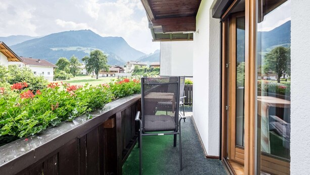 Un balcon avec une chaise, une balustrade en bois et une vue sur un paysage montagneux.