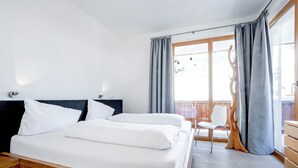 Una habitación de hotel moderna con una cama de madera, un balcón con vistas y suelo de madera.