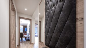 A modern hallway with a wooden bench, a tufted headboard, and a dining area in the background. - Farmhouse in Schwendau near Ski Zillertal (Mayrhofen - Schwendau)