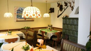 Un espace repas avec des tables et des banquettes, des lampes suspendues et des têtes d’animaux fixées aux murs.