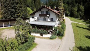 Un chalet de dos pisos con balcón, rodeado de abundante vegetación y con vistas a la montaña.