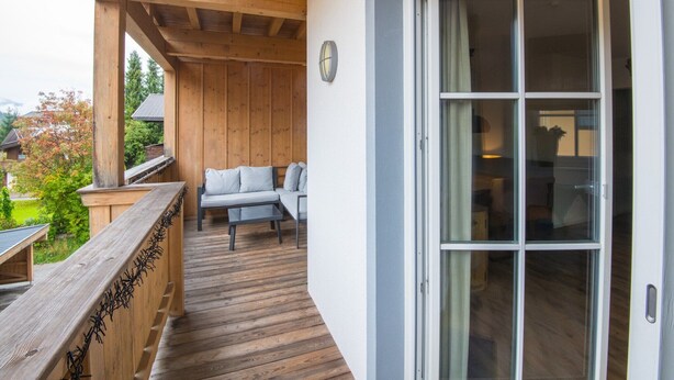 A wooden deck with a built-in bench and a sliding glass door leading to an interior space. - Modern apartment near the ski area (Brixen im Thale)