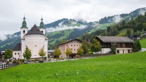 A church with two towers, a small town with houses, and a mountain backdrop. - Modern apartment near the ski area (Brixen im Thale)