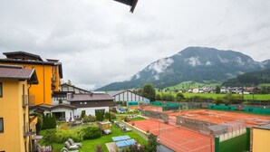 A residential area with a tennis court, a swimming pool, and a mountain backdrop. - Modern apartment near the ski area (Brixen im Thale)