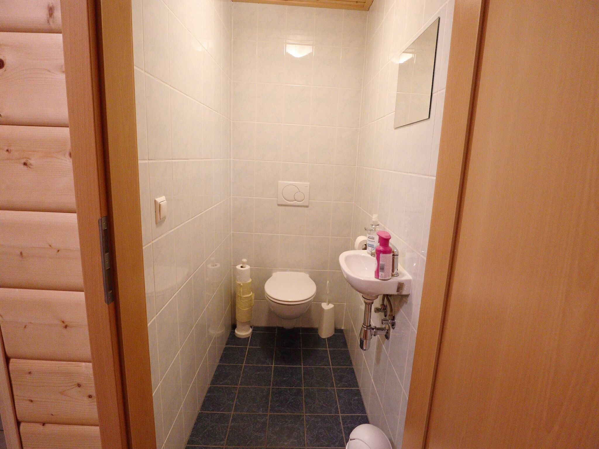 Un baño pequeño y funcional con inodoro, lavabo y espejo en la pared.
