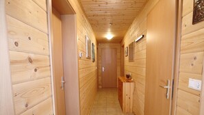 A narrow hallway with wooden walls and doors, a tiled floor, and a small wooden cabinet with a glass container on top. - Chalet in Ötztal near Ötz-Hochötz Ski Resort (Umhausen)