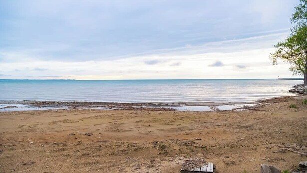 A beach with a wooden structure, clear sky, and calm water.