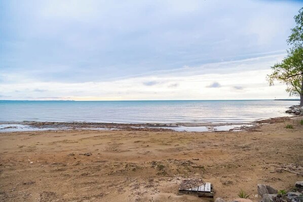 A beach with a wooden structure, clear sky, and calm water.