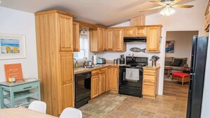 A compact kitchen with wooden cabinets, a black refrigerator, and a dining area with a table and chairs.