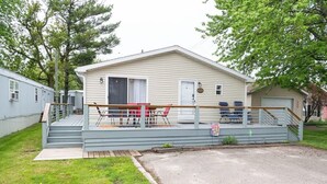 A single-story mobile home with a porch, a small deck, and a garage.