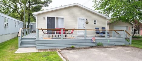 A single-story mobile home with a porch, a small deck, and a garage.