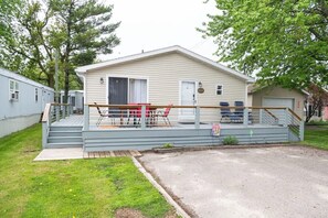 A single-story mobile home with a porch, a small deck, and a garage.