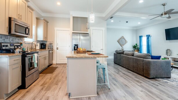 Una cocina moderna con una isla central, electrodomésticos de acero inoxidable y piso de madera clara.