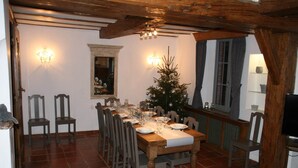 Ein Essbereich mit einem Holztisch, gedeckt für sechs Personen, umgeben von Stühlen, einer kleinen Weihnachtstanne und einem Spiegel über dem Tisch.