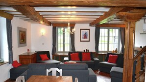 Ein gemütliches Wohnzimmer mit einem Holztisch, grauen Sofas mit roten Kissen und einer Treppe.