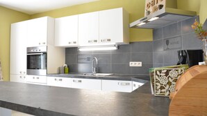 Una cucina moderna con mobili bianchi, forno integrato, angolo caffè e backsplash a tema vino.