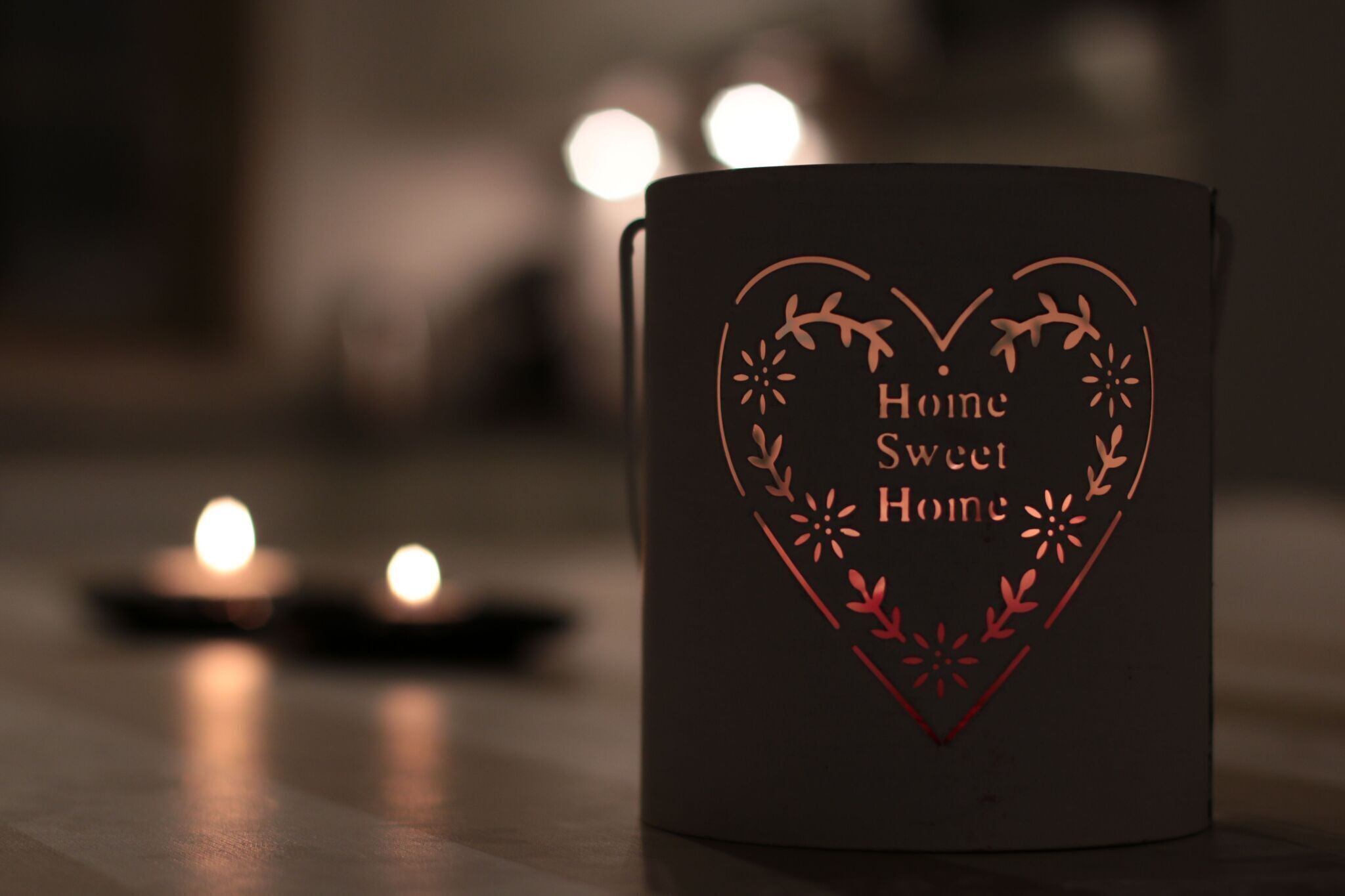 A dark-colored mug with a heart-shaped design and the text "Home Sweet Home" on a table.