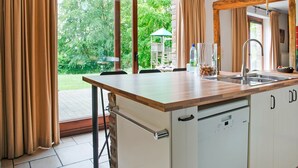 Una cocina moderna con un amplio ventanal, lavavajillas integrado y comedor con mesa y sillas.