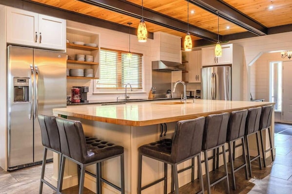 A modern kitchen with a central island, stainless steel appliances, and bar stools.