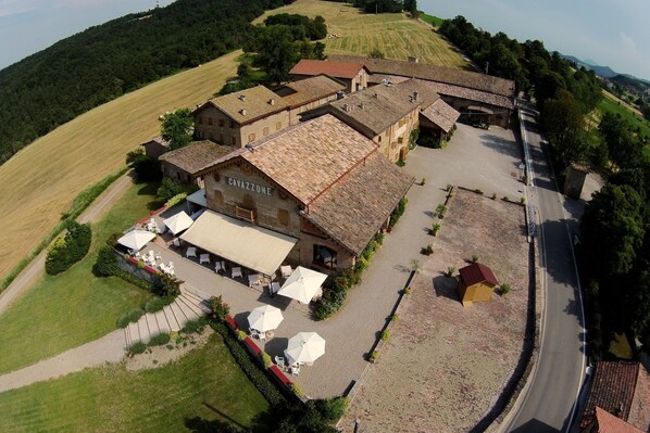 A large, historic building with a courtyard, outdoor seating, and a sign reading "CAVAZZONE".