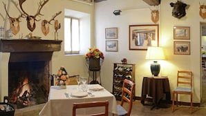 Un coin repas agrémenté d’une cheminée, d’une table dressée pour deux personnes et d’un meuble à vin en arrière-plan.