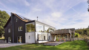 A modern two-story house with a large glass window and a wooden deck. - Comfortable chalet with indoor pool, hammam and sauna near Stoumont (Stoumont)