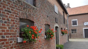Ein Backsteinhaus mit Blumenkästen an den Fenstern und einem gepflasterten Innenhof.