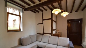 Ein modernes Wohnzimmer mit einem Ecksofa, einem Couchtisch mit Kerzen und freiliegenden Holzbalken an der Decke.