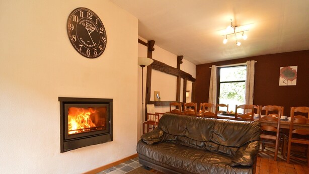 Ein gemütliches Wohnzimmer mit Kamin, Ledersofa und einem Essbereich mit Holzsesseln.
