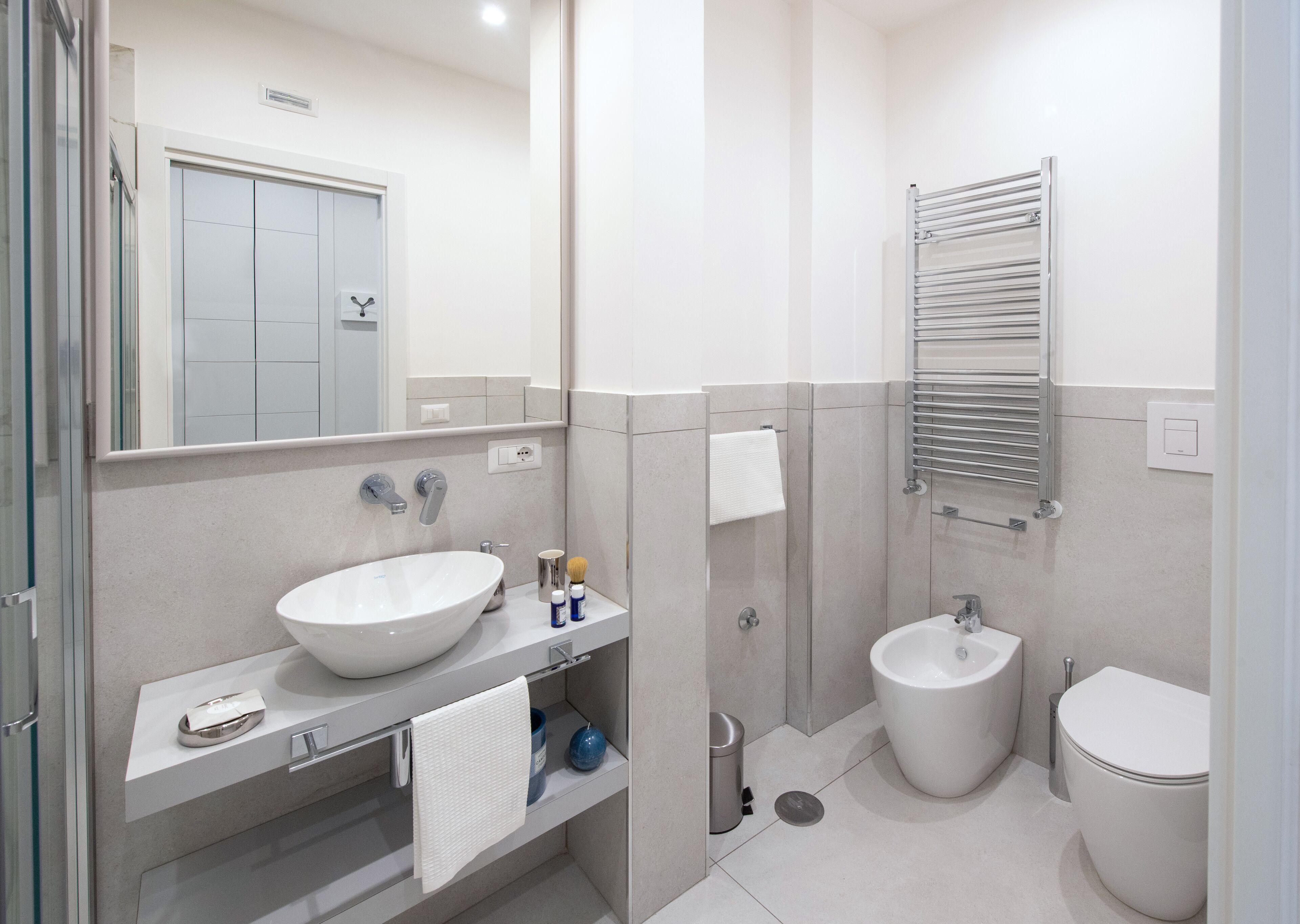 A modern bathroom with a large sink, a toilet, a bidet, and a towel rack.