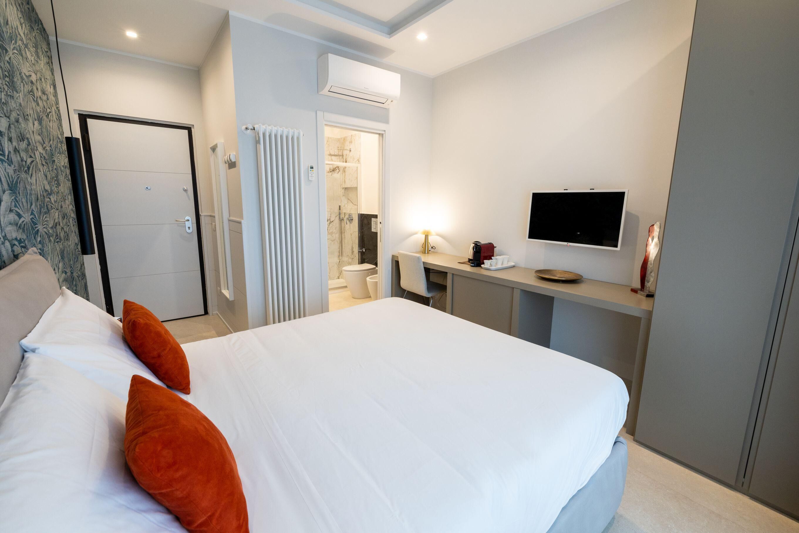 Une chambre d’hôtel dotée d’un grand lit, d’un bureau avec un téléviseur à écran plat, d’un espace douche et d’une porte donnant accès à une salle de bain.
