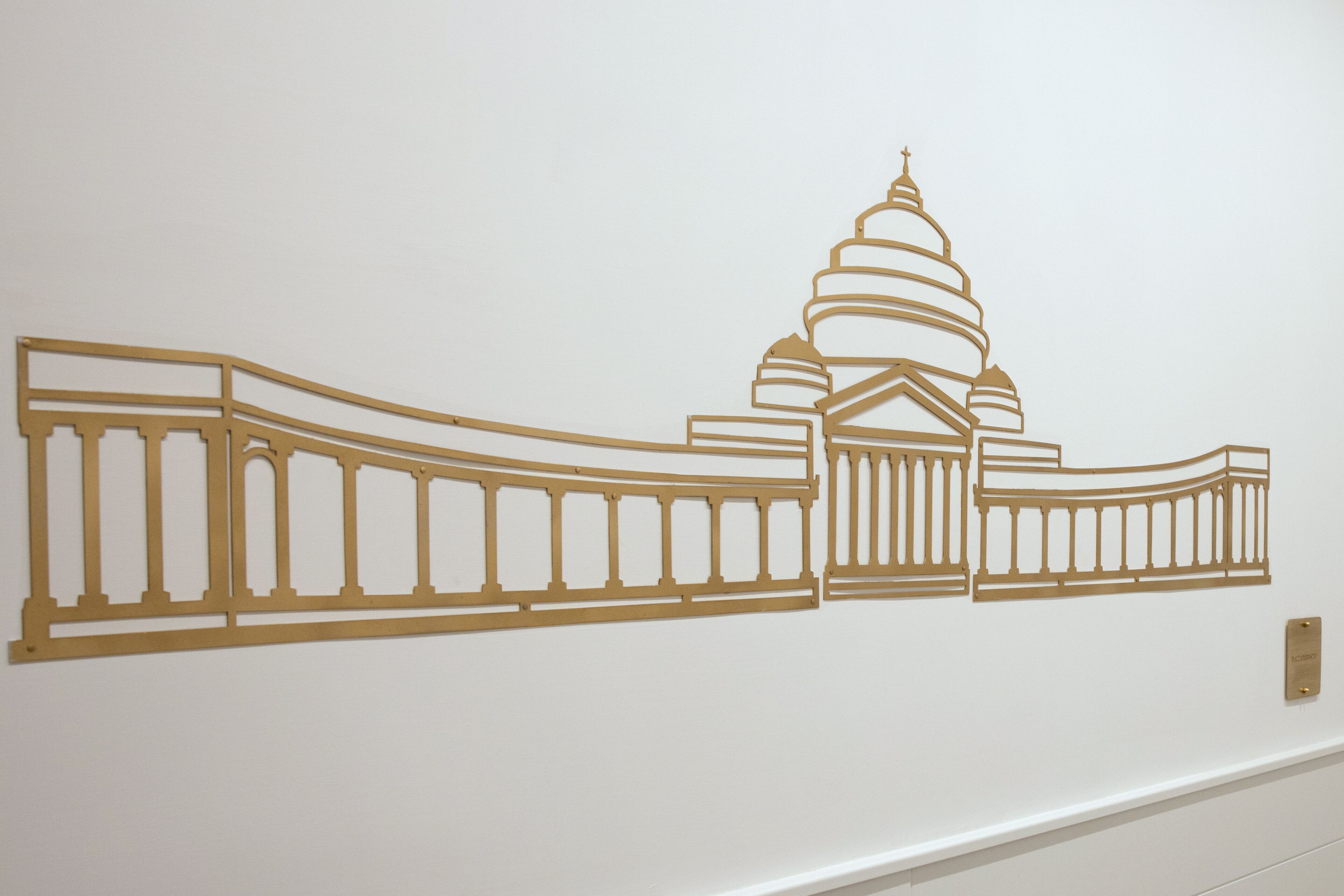 A wall with a decorative golden outline of a building with domes and columns.