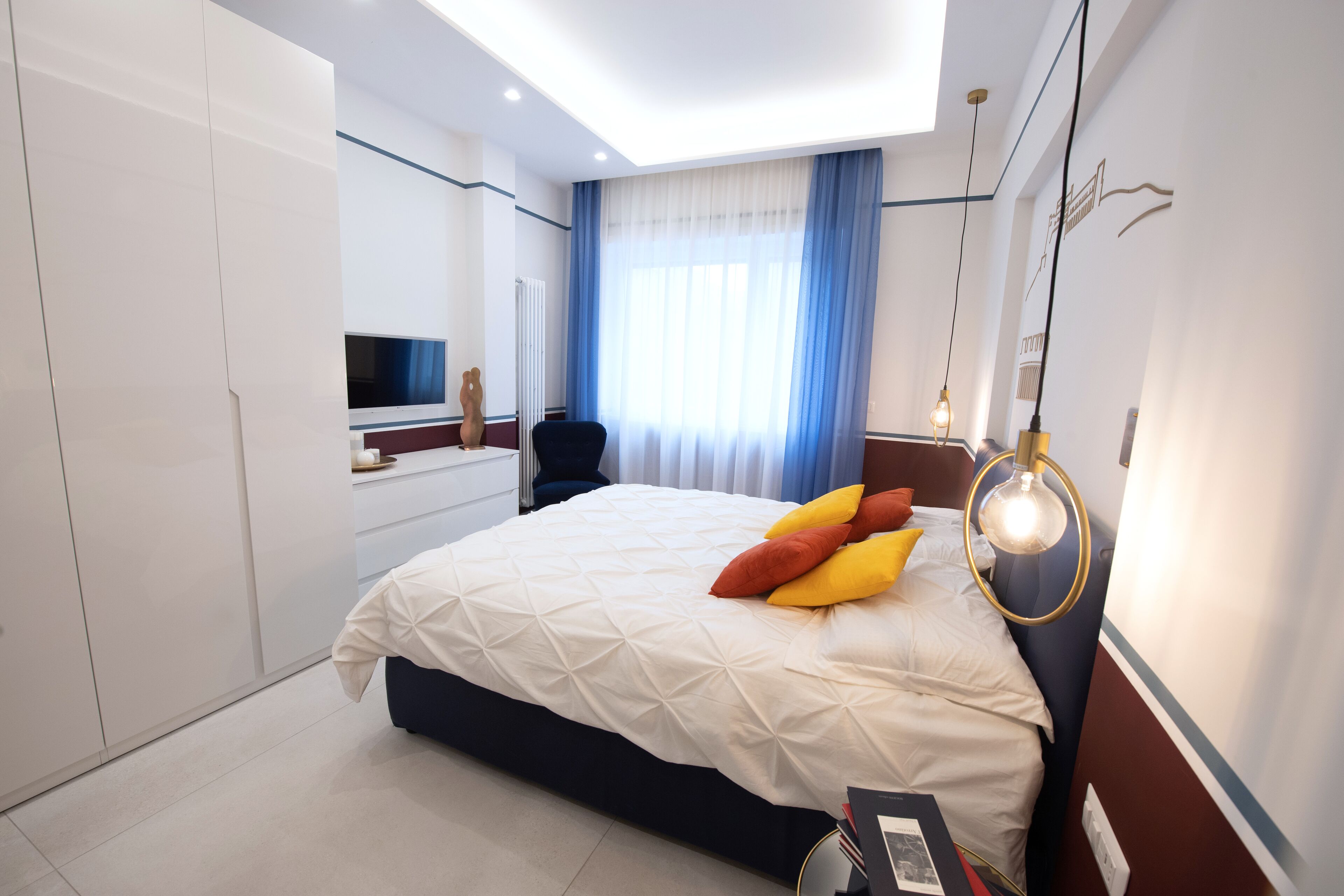 A modern bedroom with a large bed, a desk, and a TV.