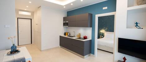 A modern apartment with a kitchen, living area, and a bedroom.