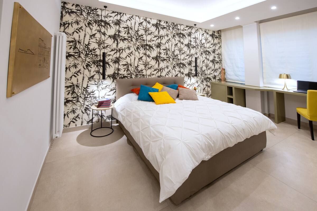 A modern bedroom with a large bed, a desk, and a chair.
