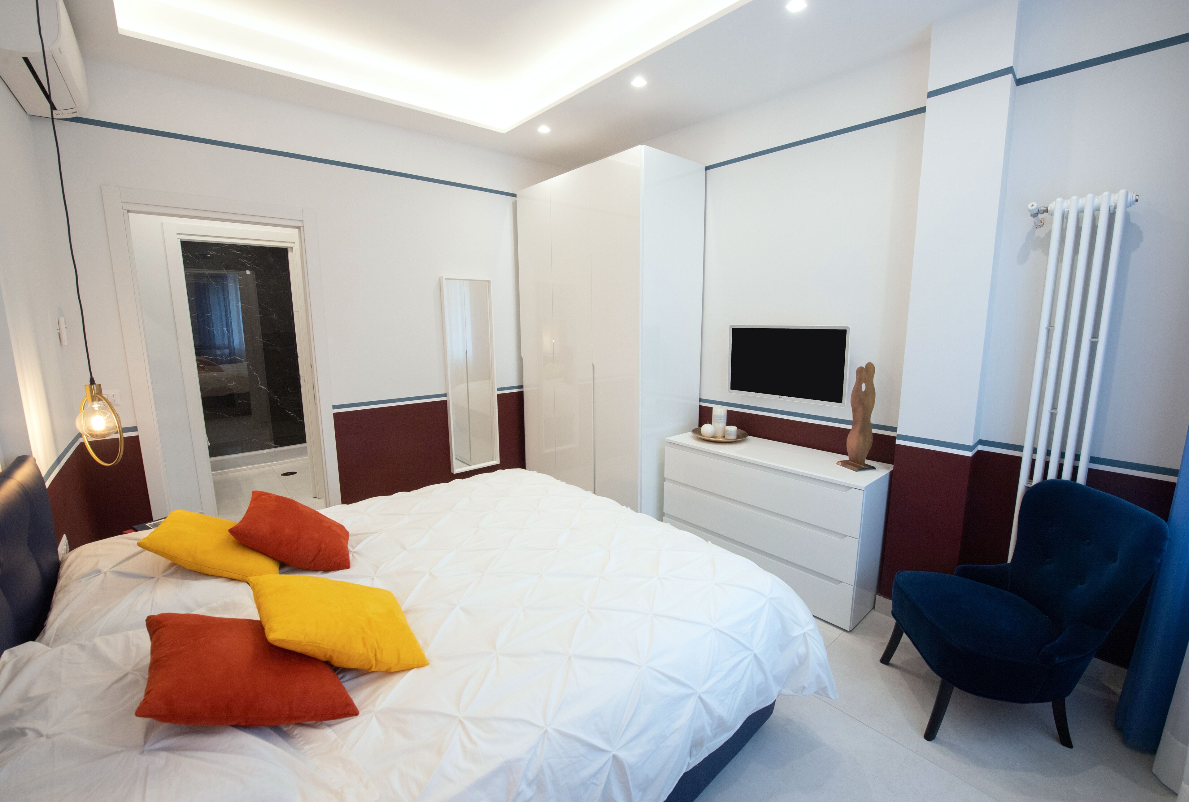A modern hotel room with a large bed, a desk, a chair, and a TV.
