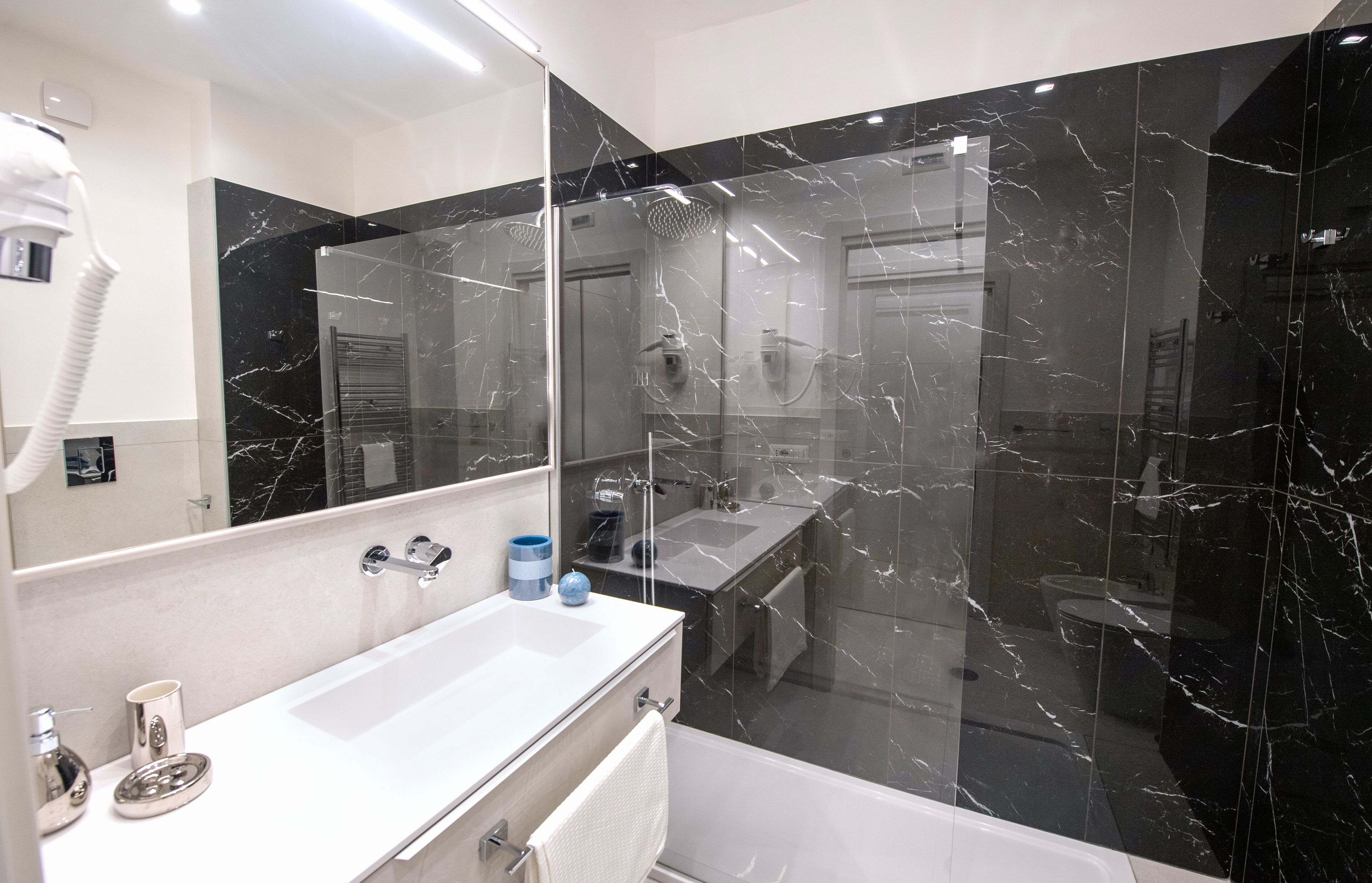 A modern bathroom with a large mirror, a white sink, and a glass-enclosed shower area.