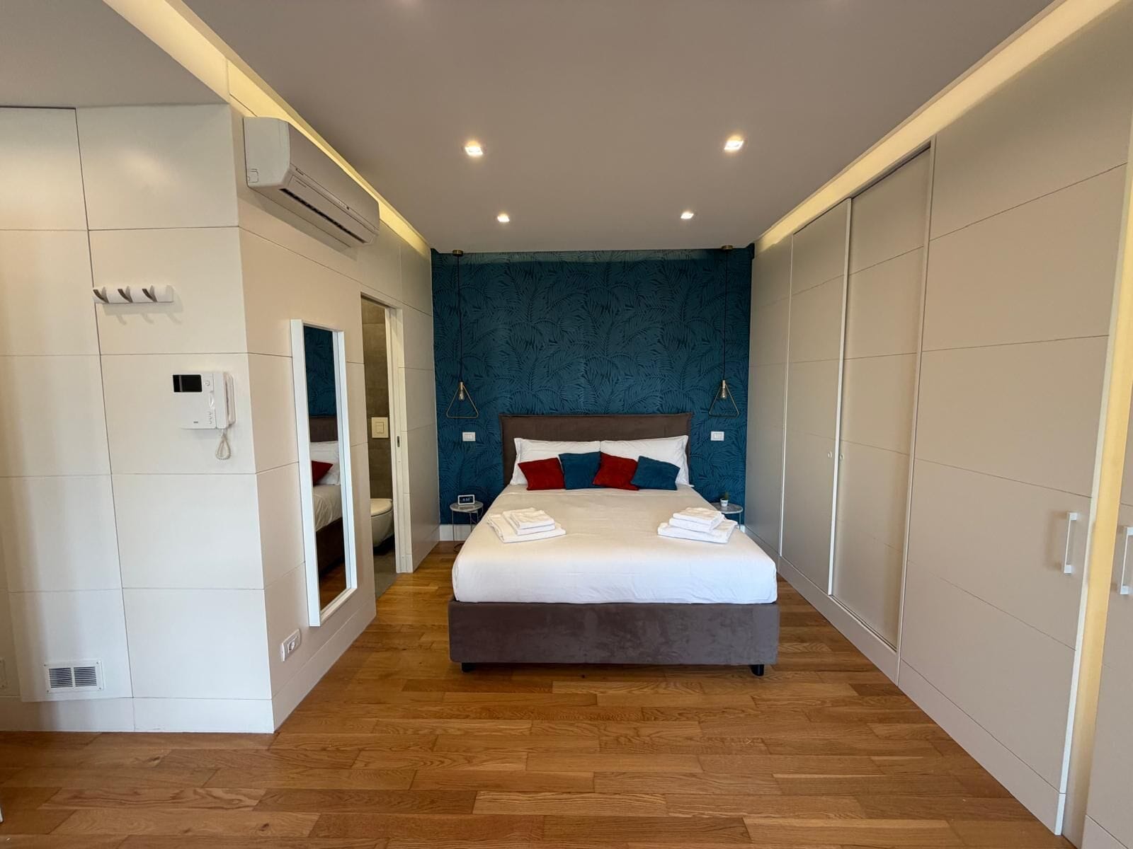 A hotel room with a bed, a bathroom, and a wardrobe.