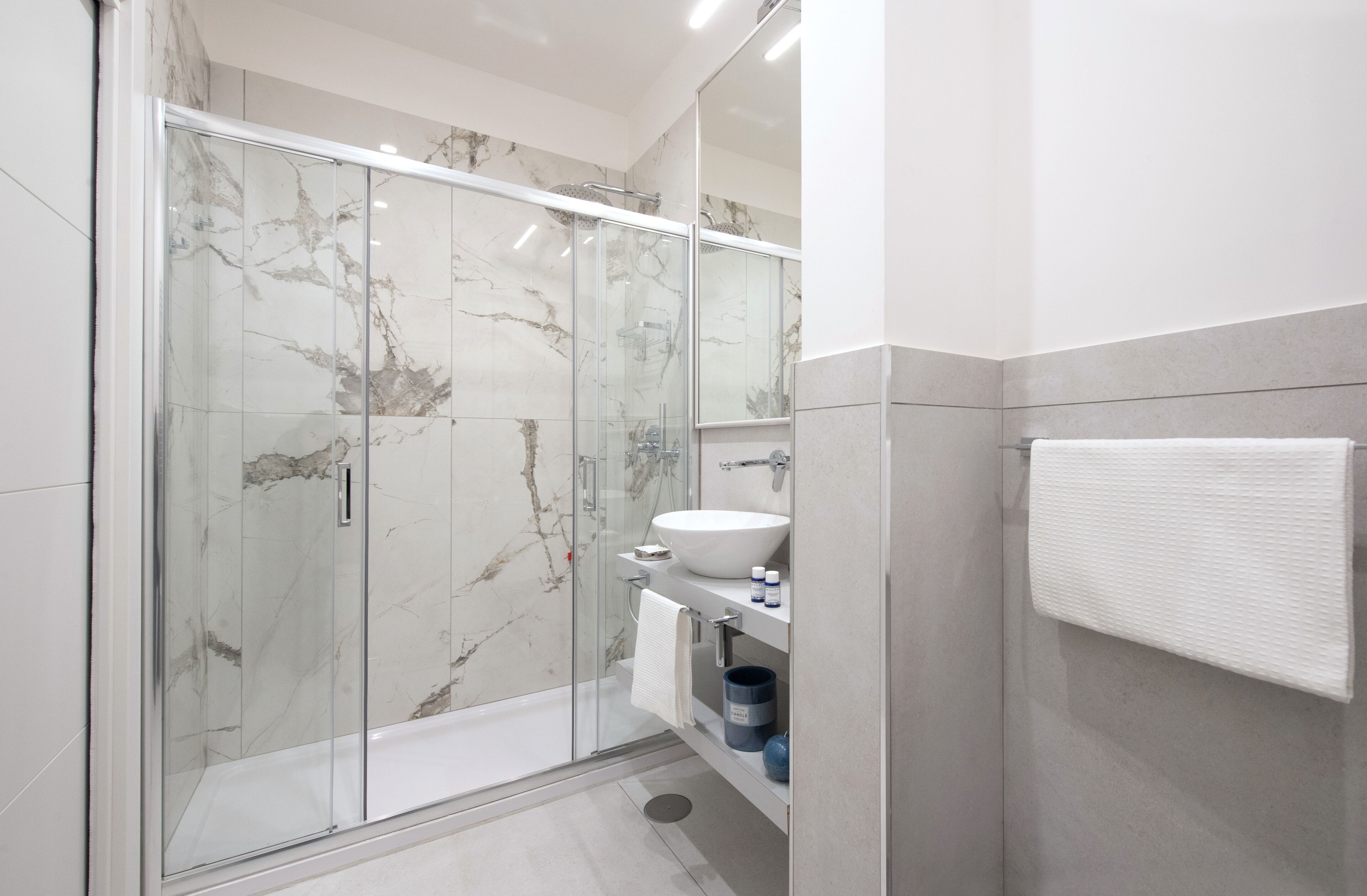 A modern bathroom with a glass-enclosed shower, a white sink, and a towel rack.