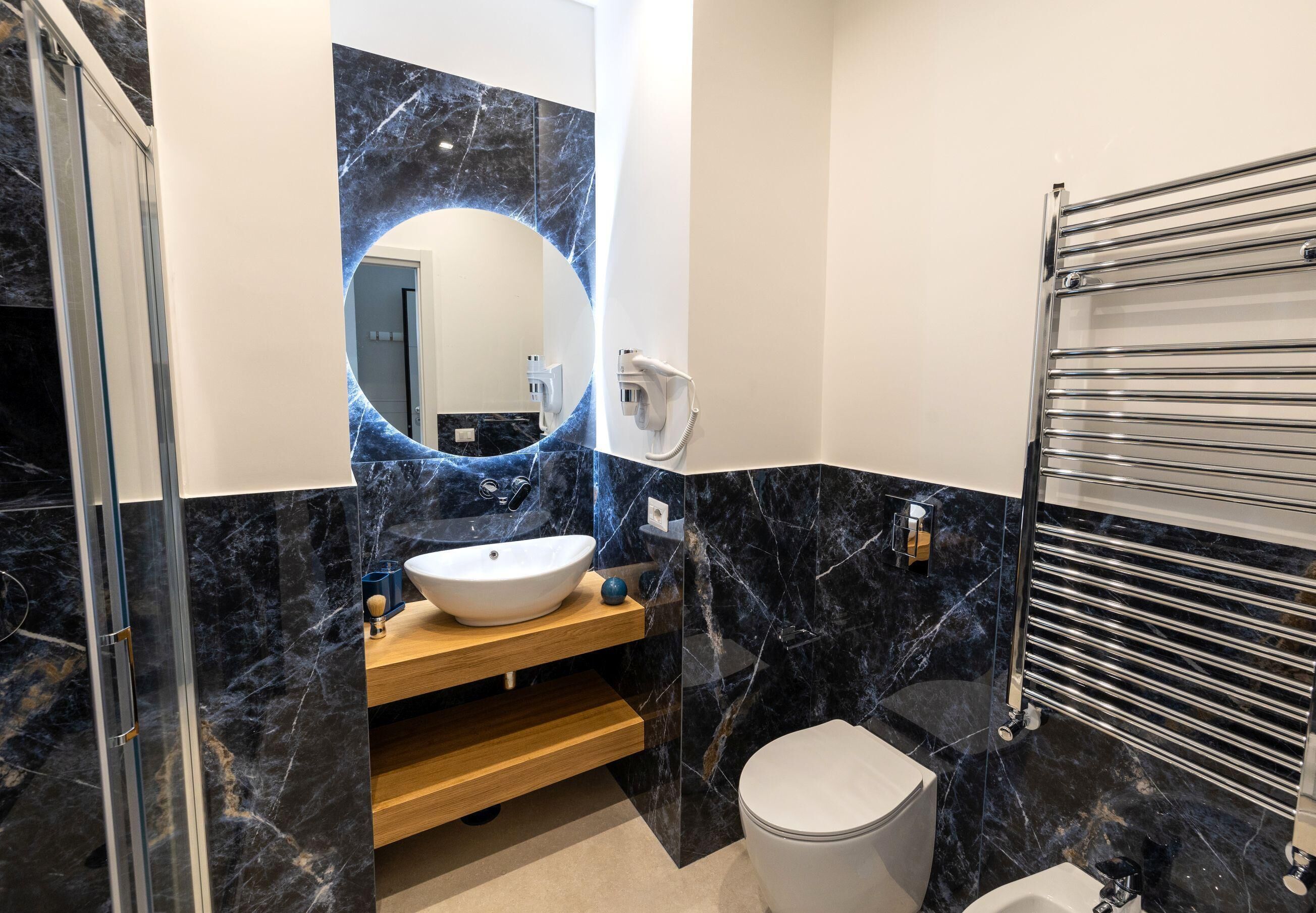 Une salle de bain moderne avec un grand miroir, un lavabo blanc, des toilettes et un espace douche.