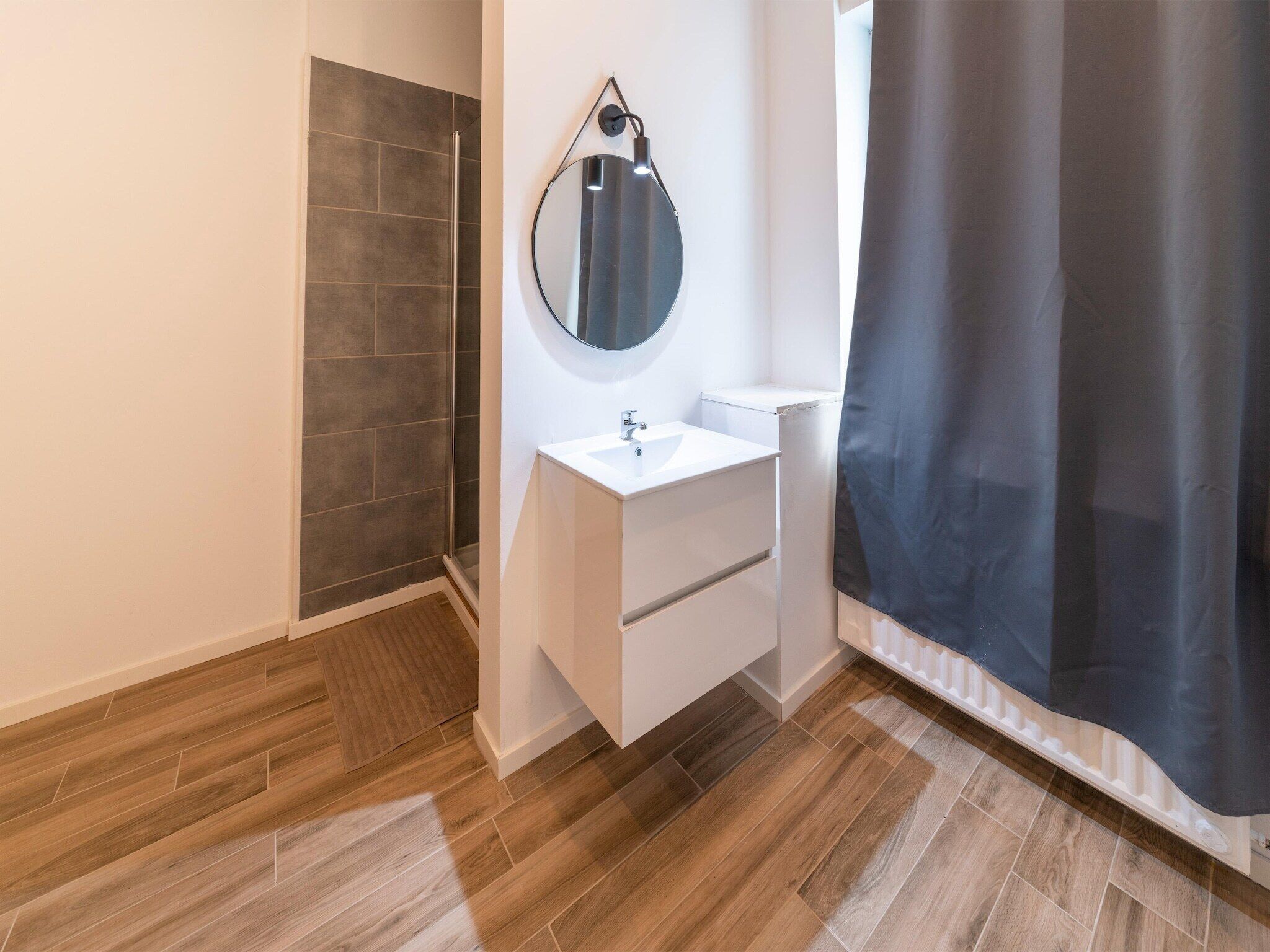Un baño moderno con ducha, lavamanos y espejo.