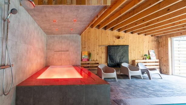 Un espace spa moderne doté d’un plancher chauffant, d’une piscine et de murs en bois.