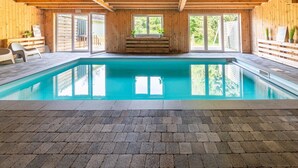 Une piscine intérieure avec des murs en bois et un sol carrelé.