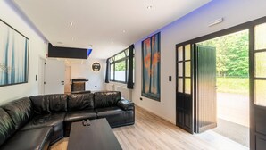 Un salon moderne avec un canapé d’angle en cuir noir, une table basse en bois et des œuvres d’art accrochées aux murs.