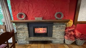 A stone fireplace with a fire, surrounded by baskets and wrapped gifts.