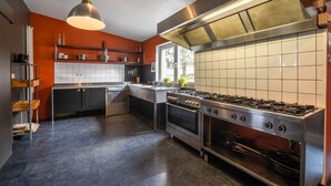 A modern kitchen with stainless steel appliances, a large window, and a bright pendant light.